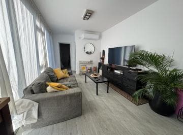 Cocina moderna con madera cálida, mesada de concreto y grifería negra.